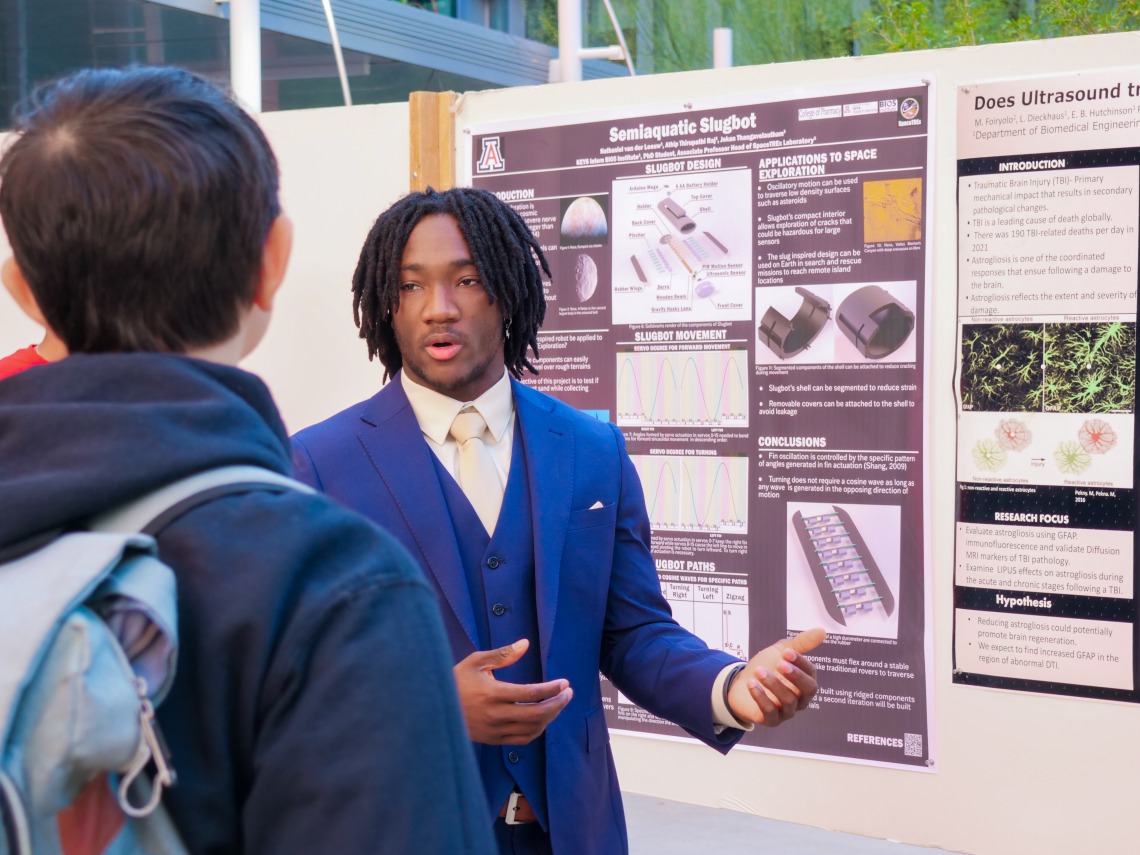 Young man discusses his research poster 