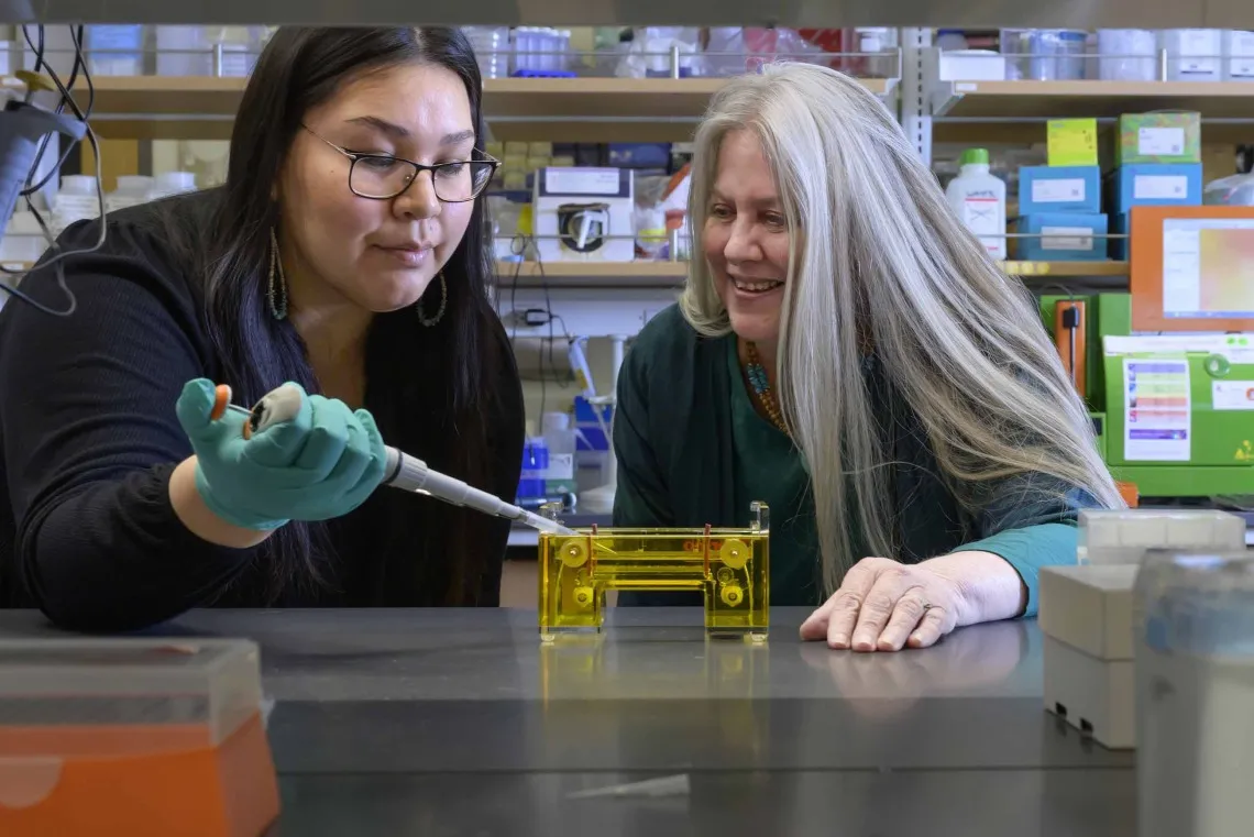 Angel-Grace Charity Leslie is pipetting under the supervision of Kathleen Rodgers, PhD