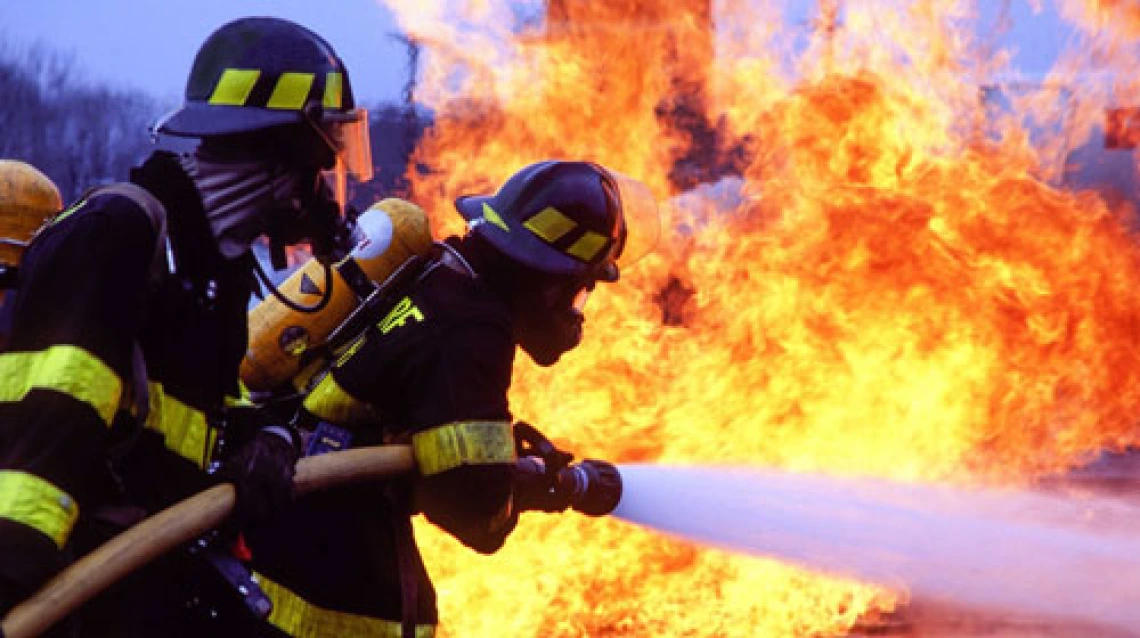 Firefighters fighting a fire with a large hose