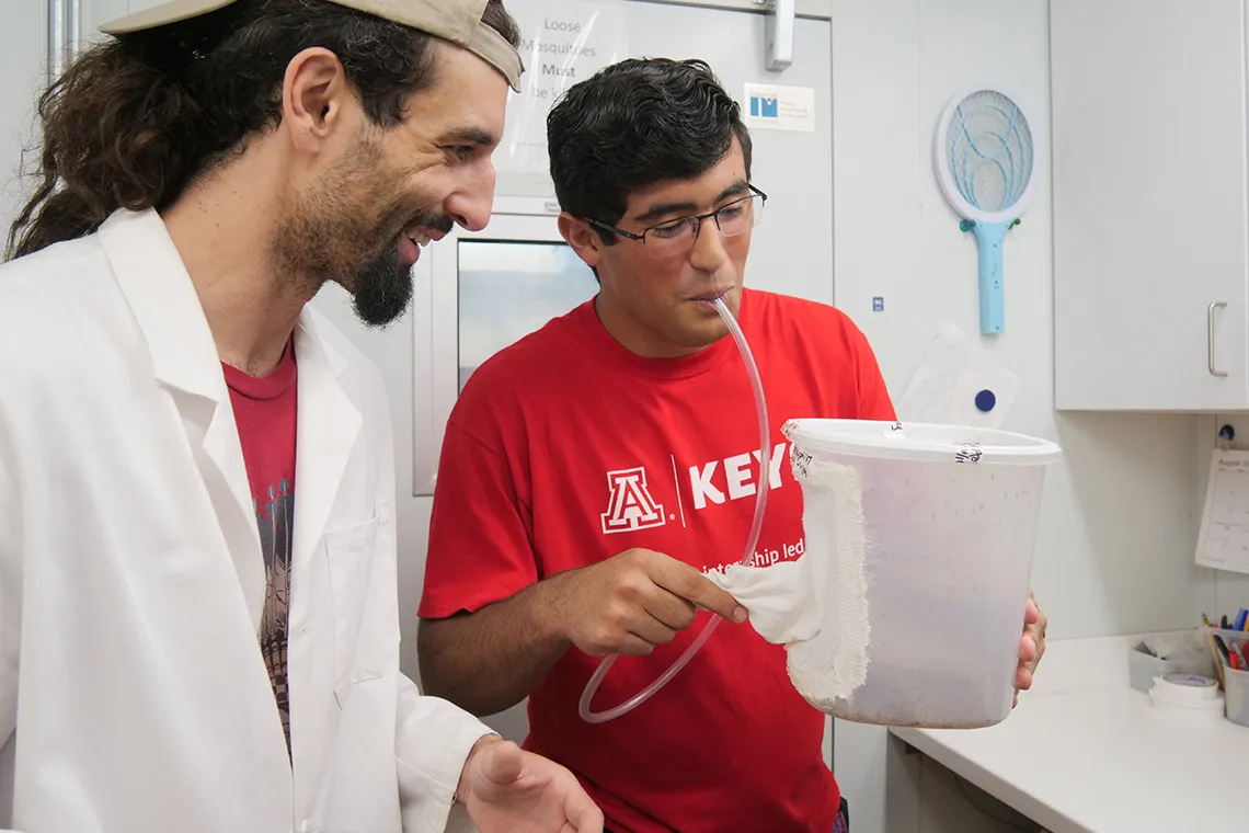 high school student working with a researcher in a lab