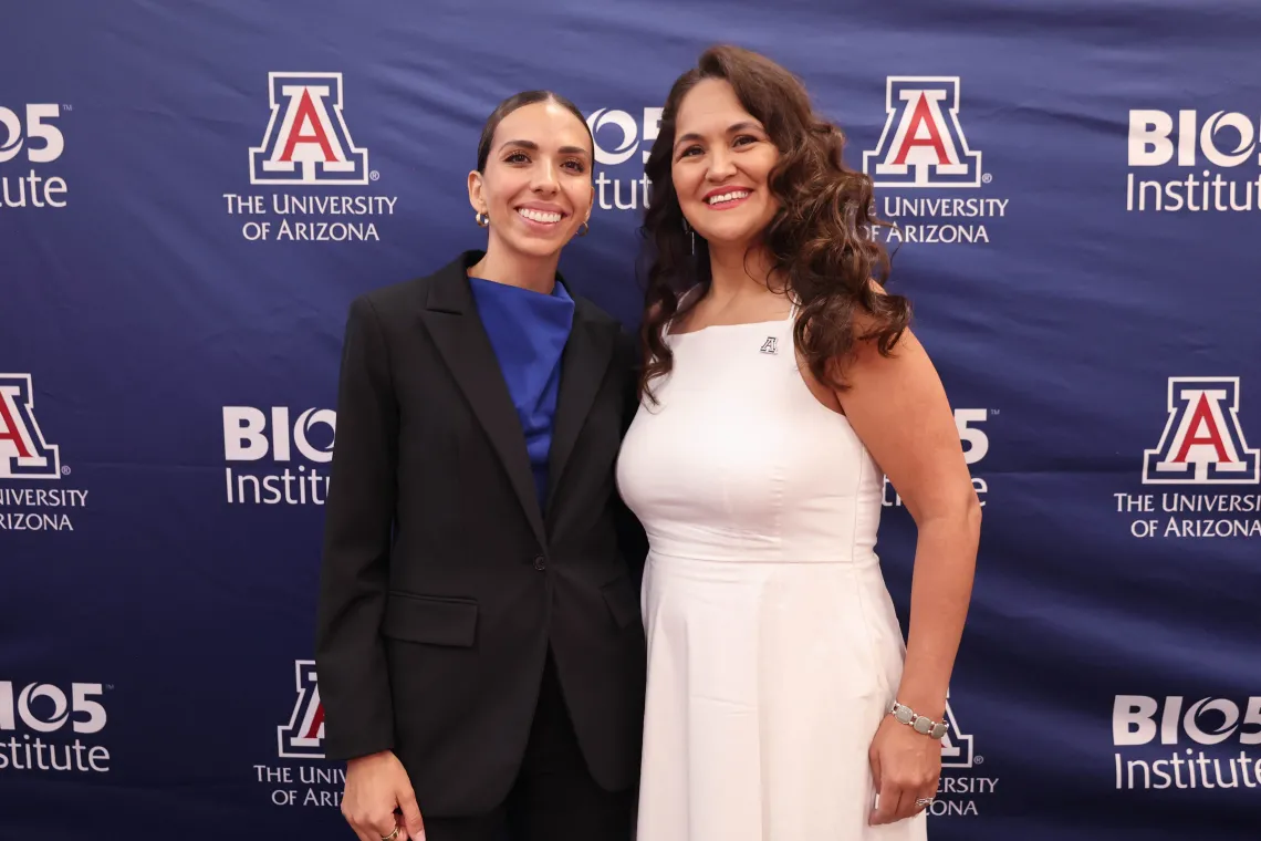 Two women pose in front of a sign with the BIO5 Institute logo