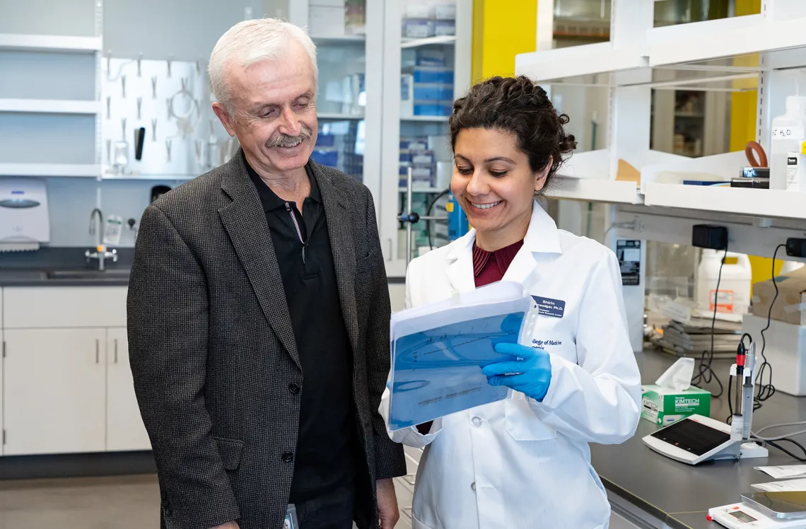 Two researchers, one holding a folder, smiling and discussing in a laboratory.