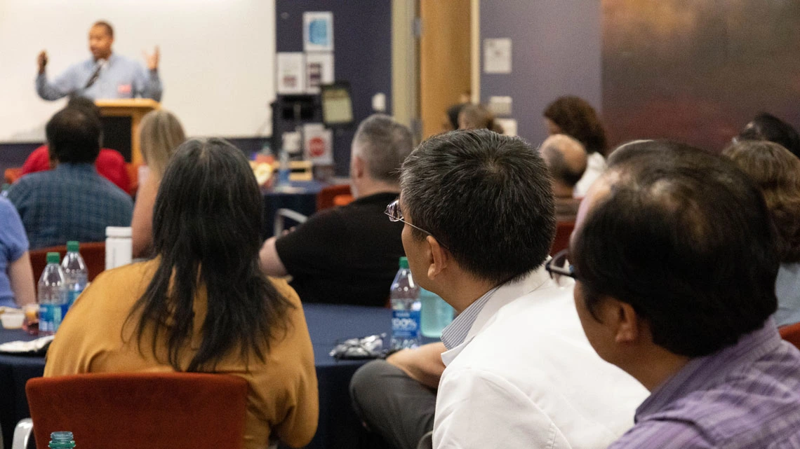 Group of people listen intently to a person speaking at the podium