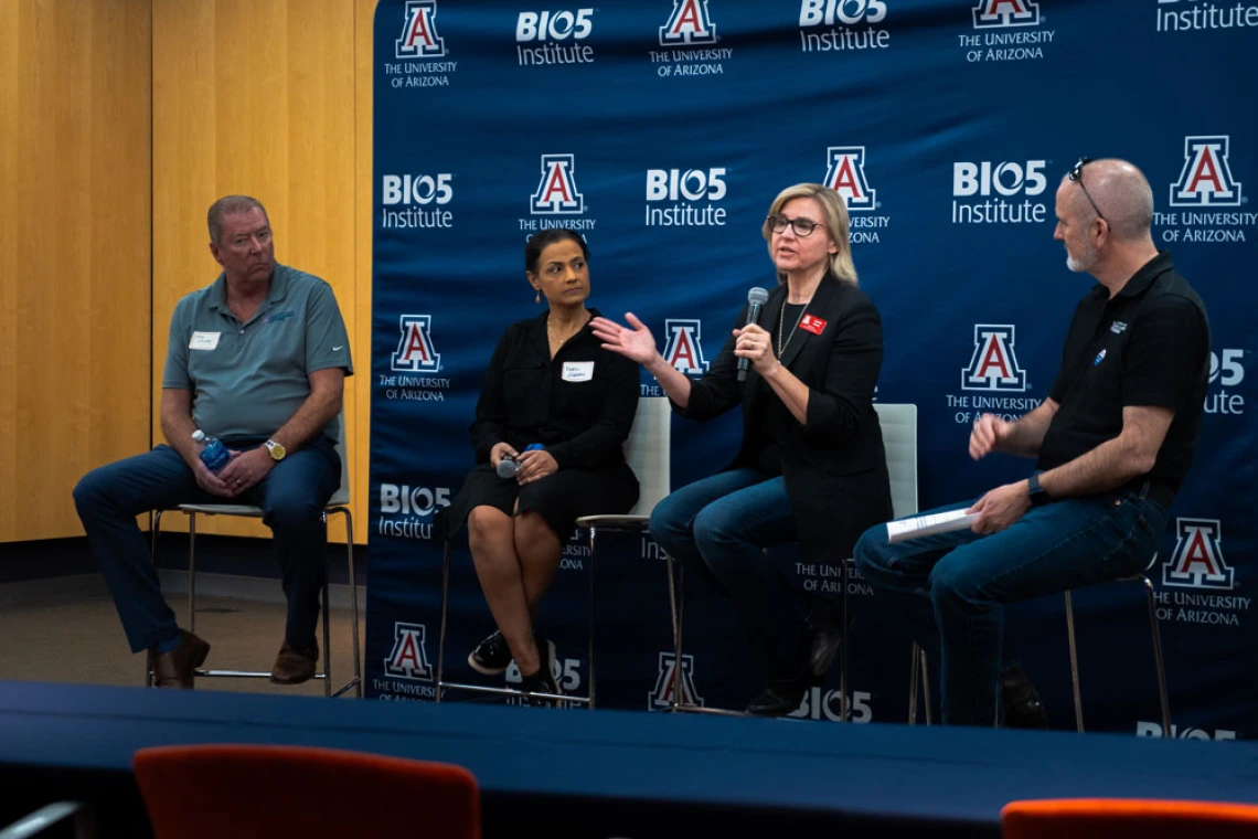 Four individuals participating in a panel discussion at the University of Arizona's BIO5 Institute. The panelists are seated on stage with microphones, in front of a backdrop featuring the BIO5 and University of Arizona logos.