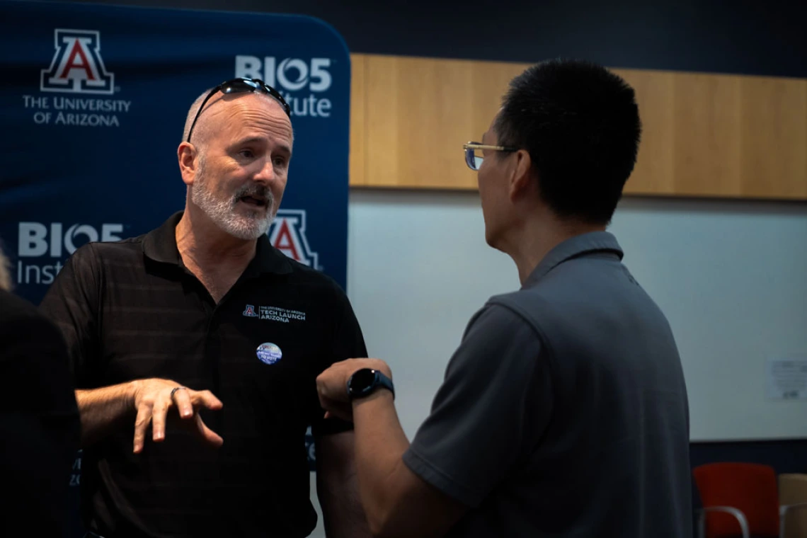 Two individuals are engaged in a conversation at a University of Arizona BIO5 Institute event.