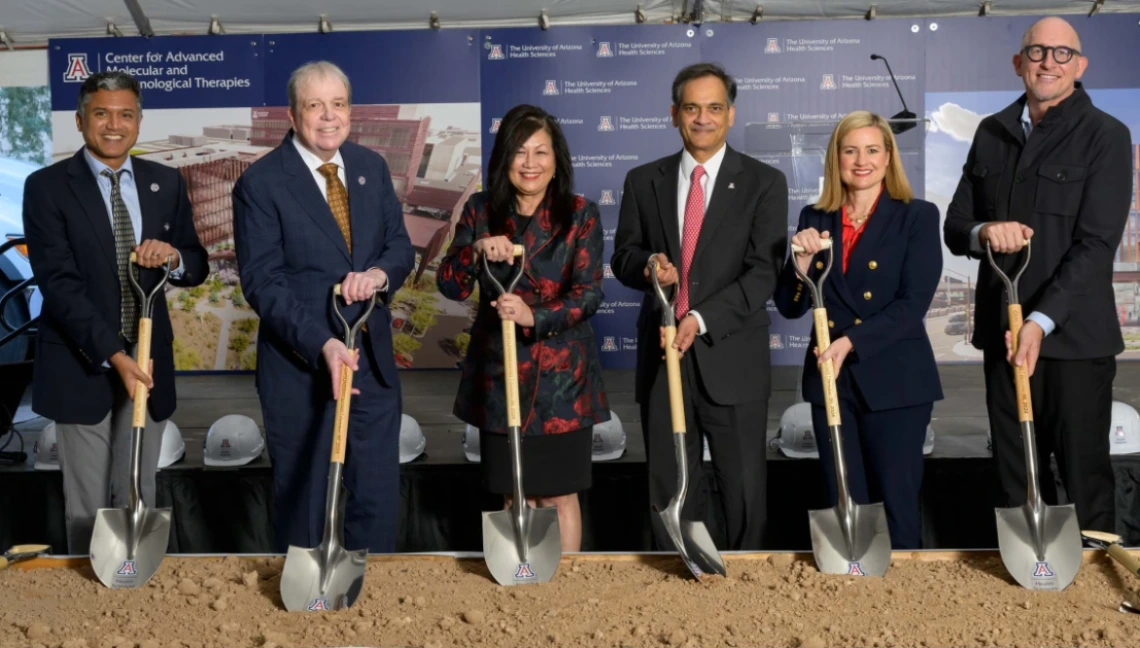 A group of people in professional attire holding shovels for a breaking ground ceremony