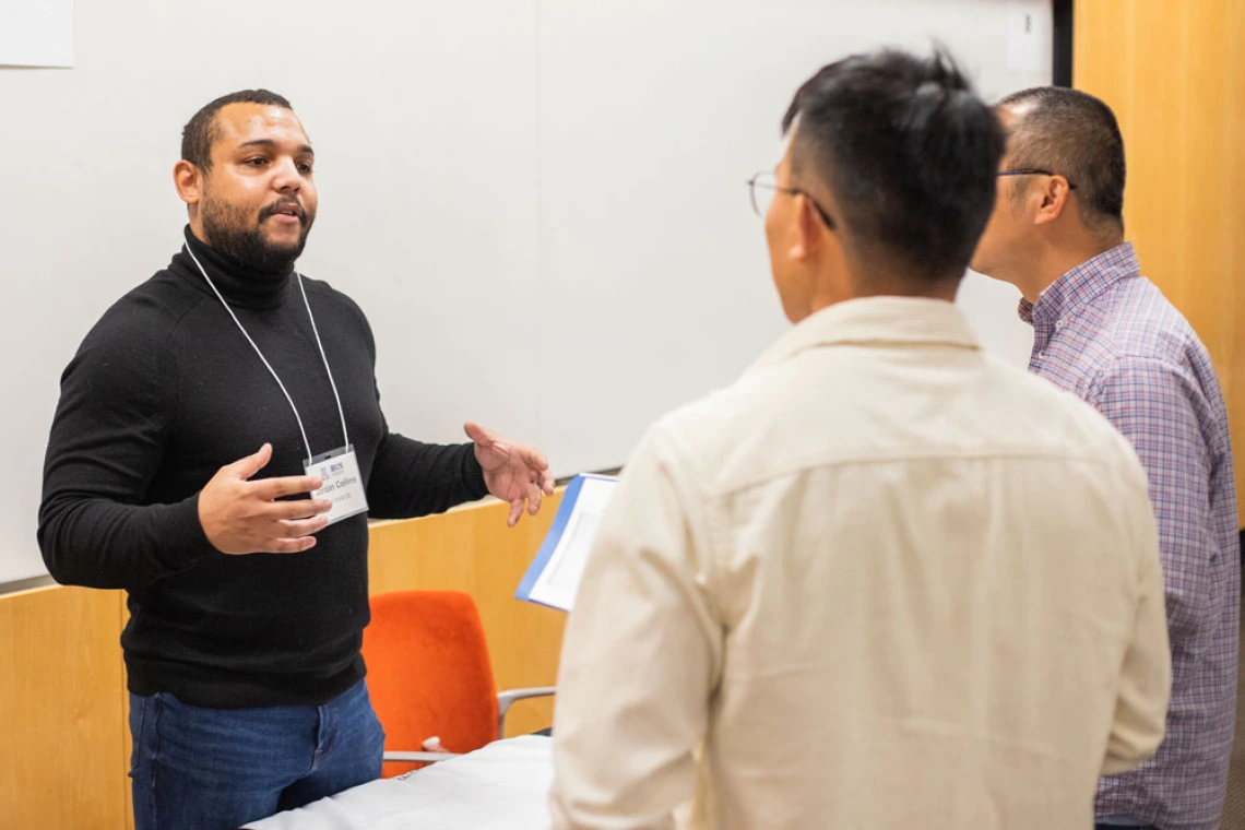 Three individuals engaged in a discussion at a professional event, one of them is presenting or explaining a point.