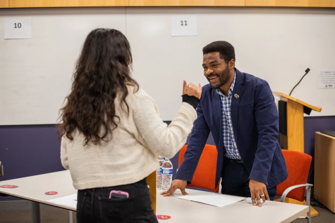 Person smiling and chatting with another person across a table in at Student Industry Networking Event.