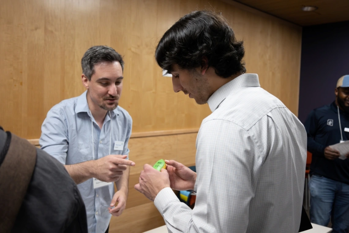 Two individuals examining a green electronic device at a conference.
