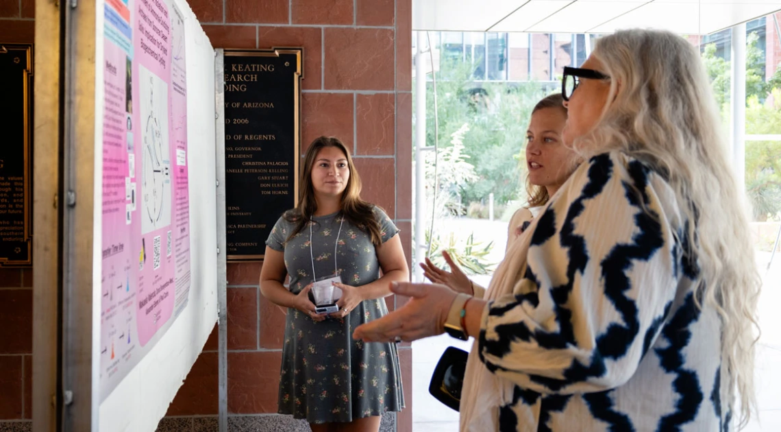 Several people discussing a research poster at the BIO5 Institute's Research & Innovation Showacse