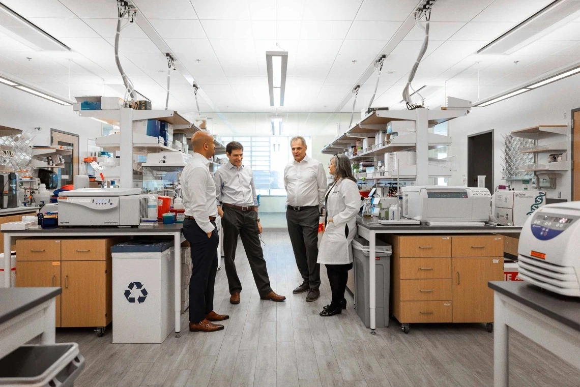 Four professionals having a discussion in a well-equipped laboratory.