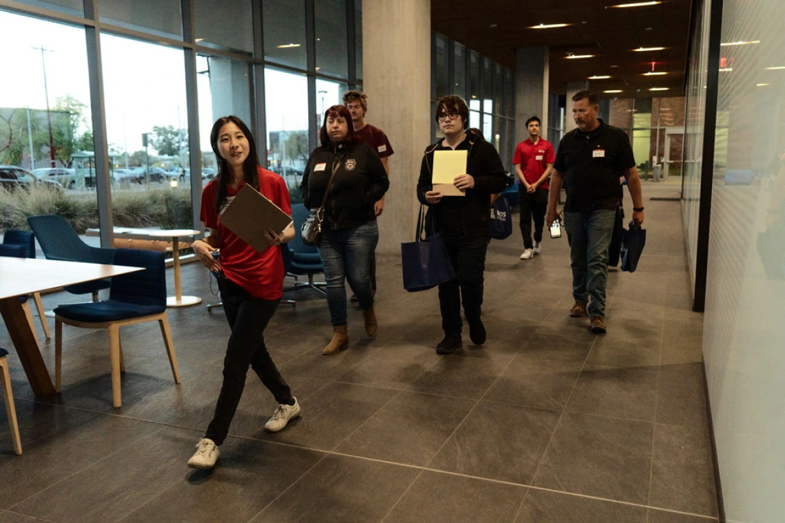 Person in a red shirt and holding a clipboard leading a tour