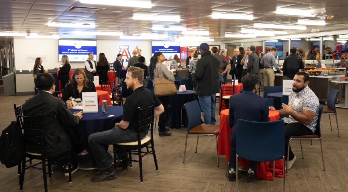 Faculty, industry partners, and community members are gathered in small groups connecting and engaging with each other. 