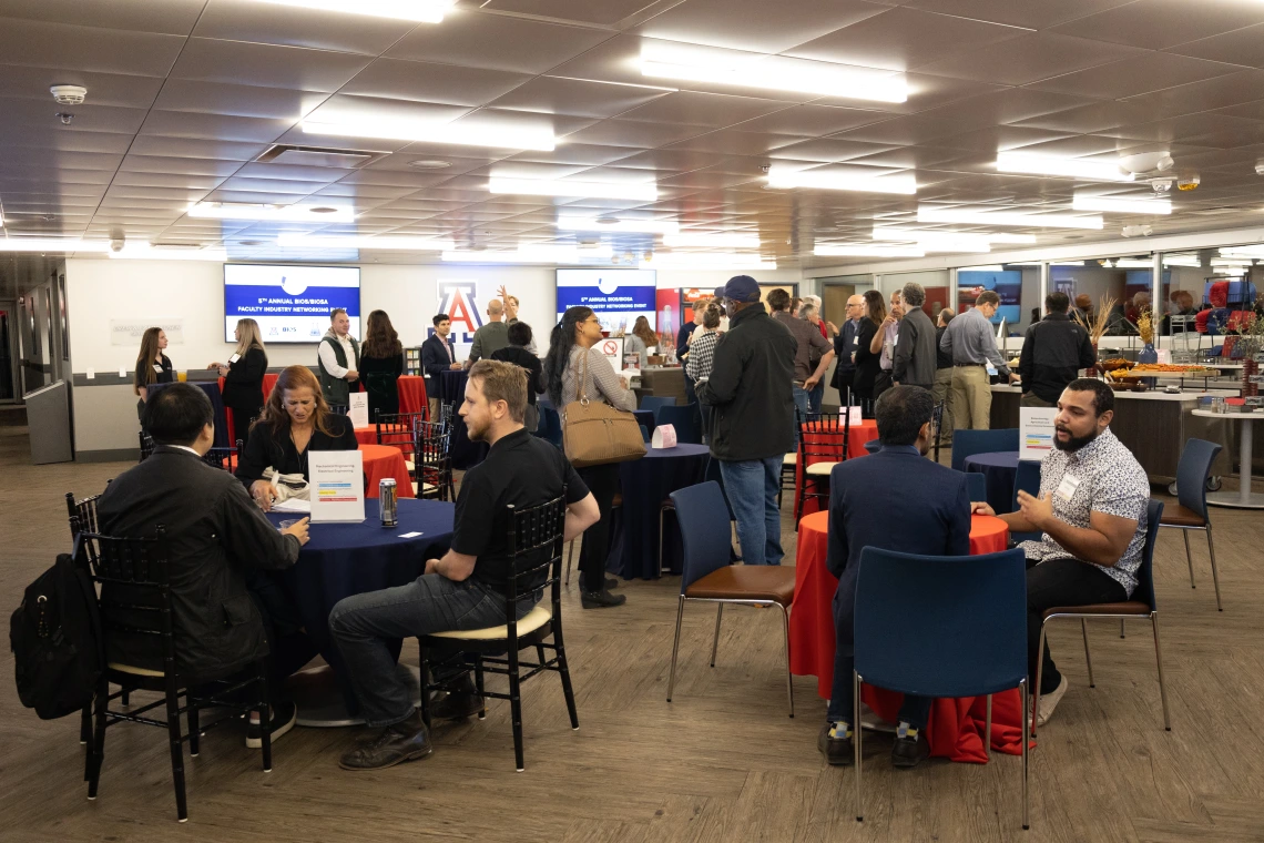 Faculty, industry partners, and community members are gathered in small groups connecting and engaging with each other. 