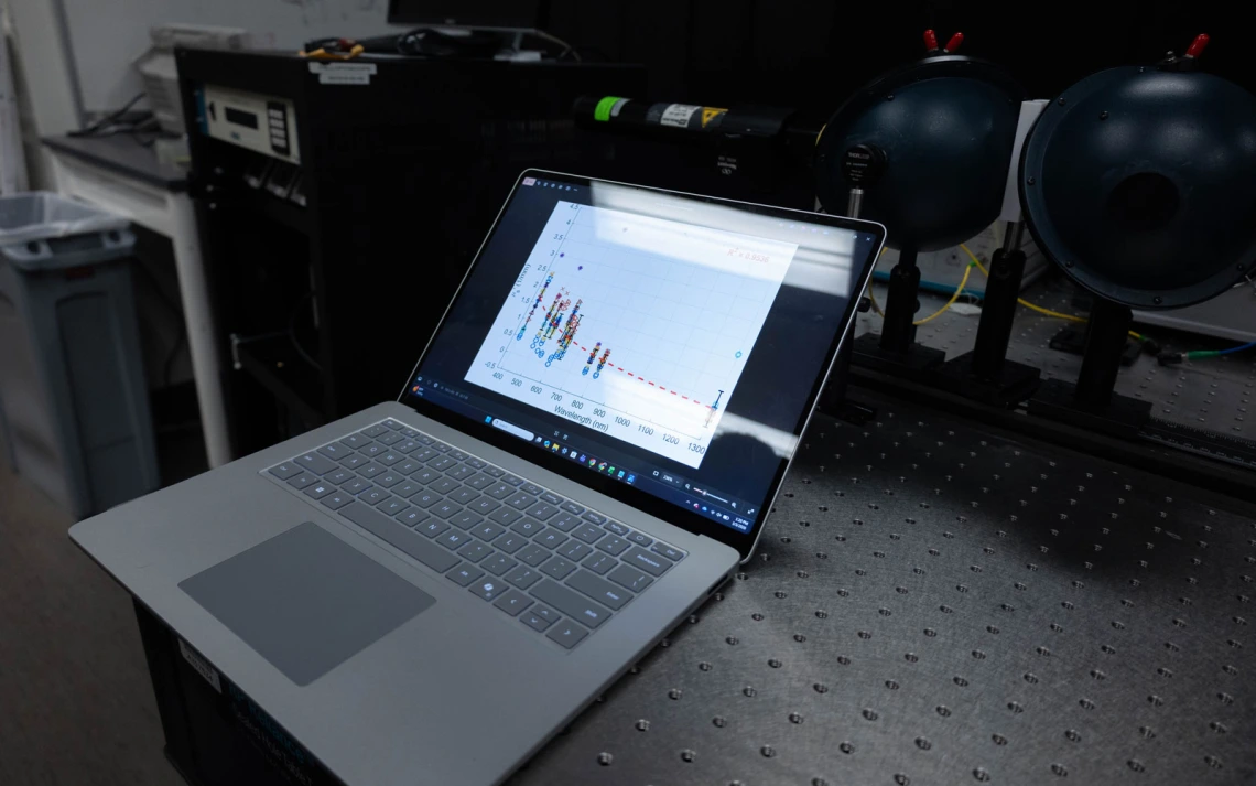 A laptop on a textured table displays a colorful scatter plot graph.
