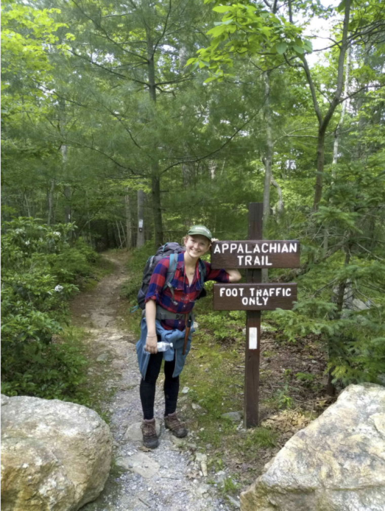 Erika Haws in forest standing next to Appalachian Trail sign