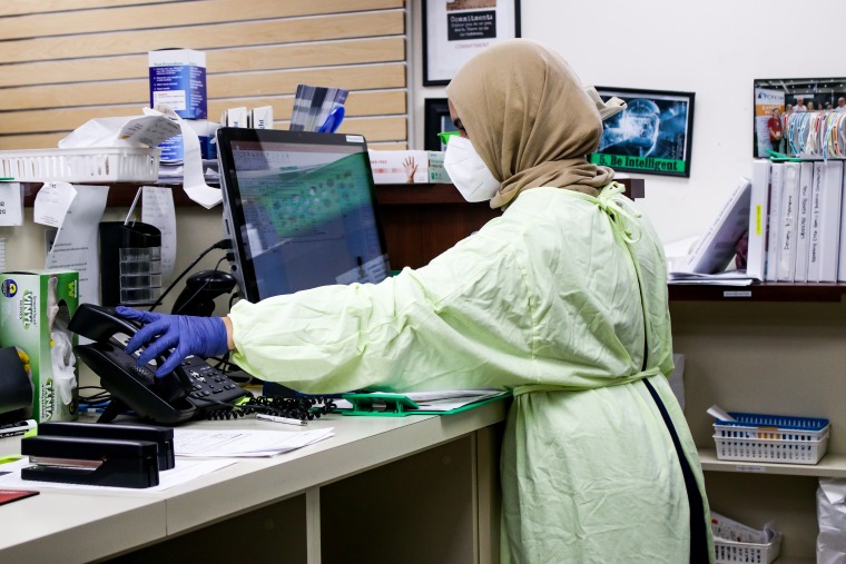 Lady wearing full body suit and mask working at desk