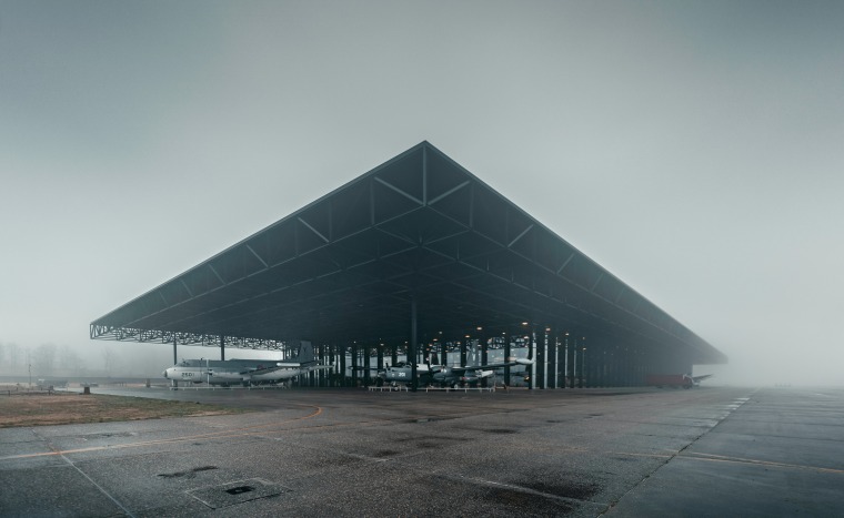 Foggy scene with airplanes sitting in a large airplane hangar