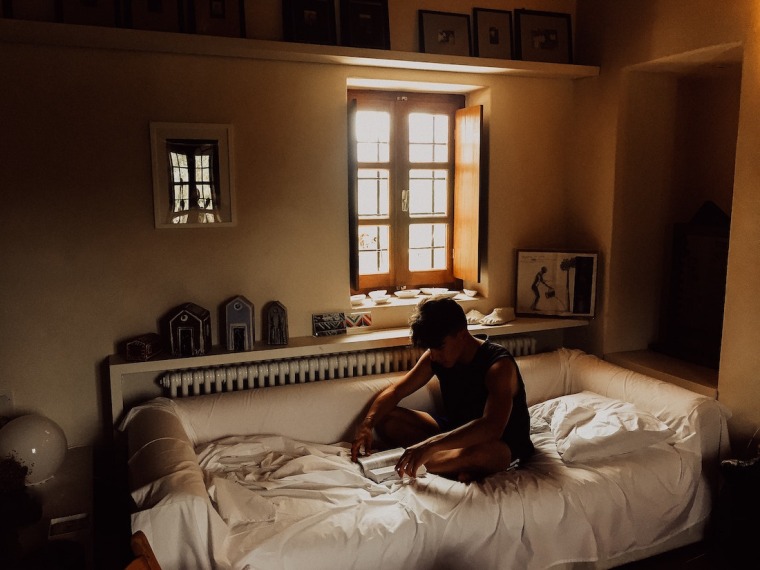 Man in bed with light coming through window.