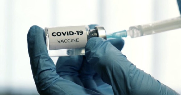 Vile of Covid-19 vaccine in front of syringes 