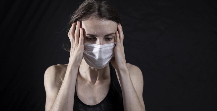 Woman wearing mask with a headache.