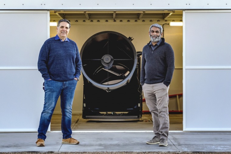 Drs. Roberto Furfaro and Vishnu Reddy standing in front of a large, black device