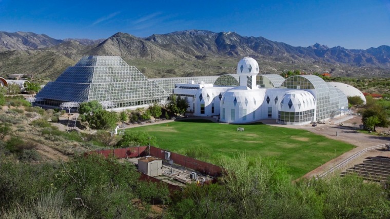 Arial shot of Biosphere 2, a glass-domed and pyramid structure in the middle of green desert and mountains