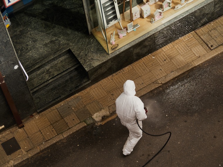 Worker in full suit spraying disinfectant.