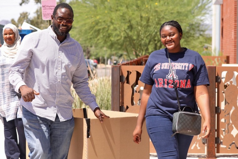 Student and their father walking towards camera with move-in equipment. 