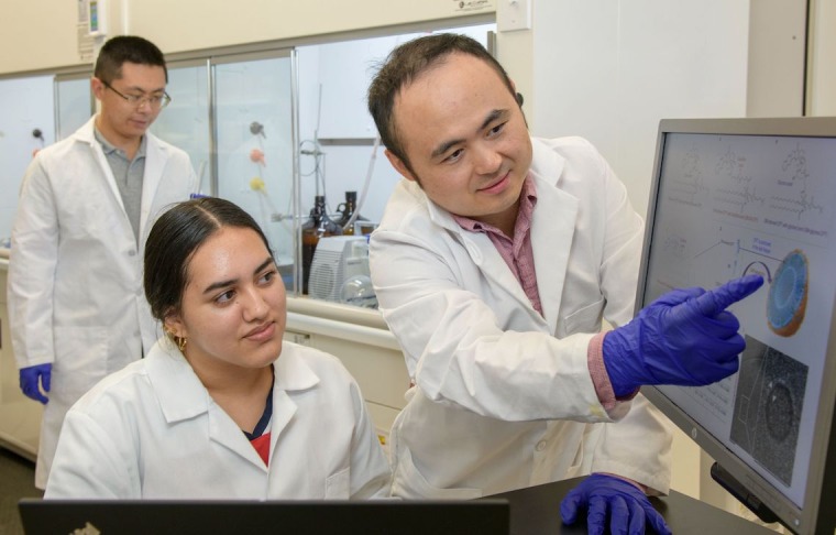 Dr. Jianqin Lu in a lab with other researchers.