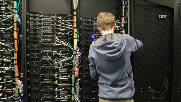 Person working on a wall of computer servers.