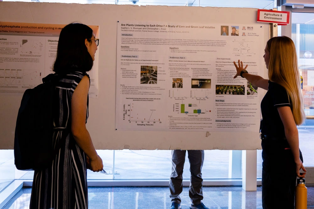 Two individuals are viewing and discussing scientific posters at a conference.