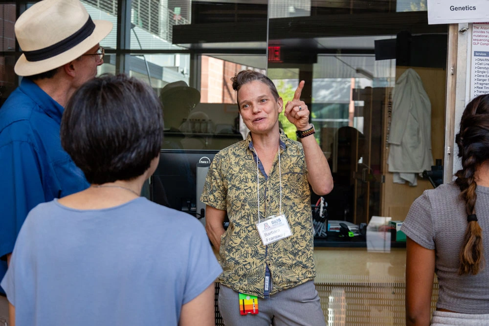 Person at the BIO5 Institute gestures and explains an exhibit to a group of attentive visitors.