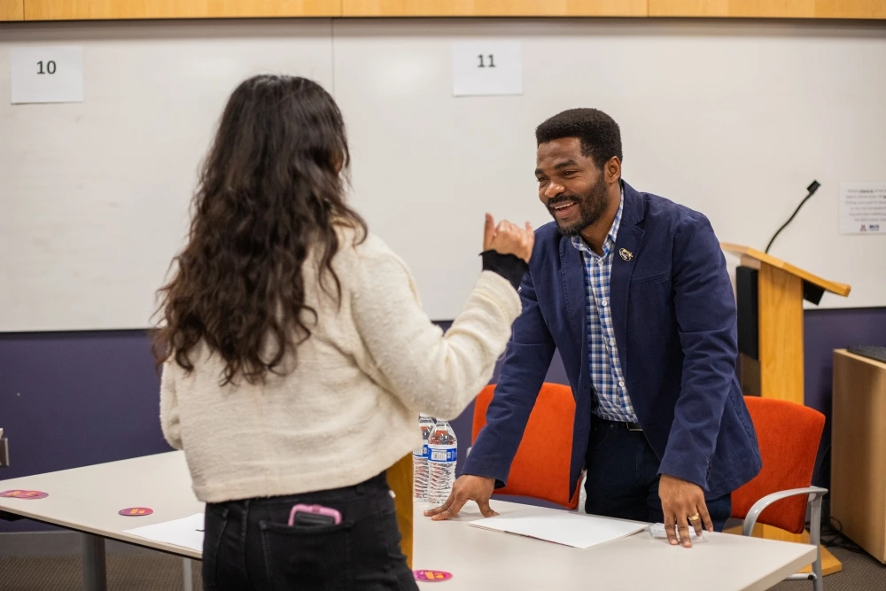 Person smiling and chatting with another person across a table in at Student Industry Networking Event.