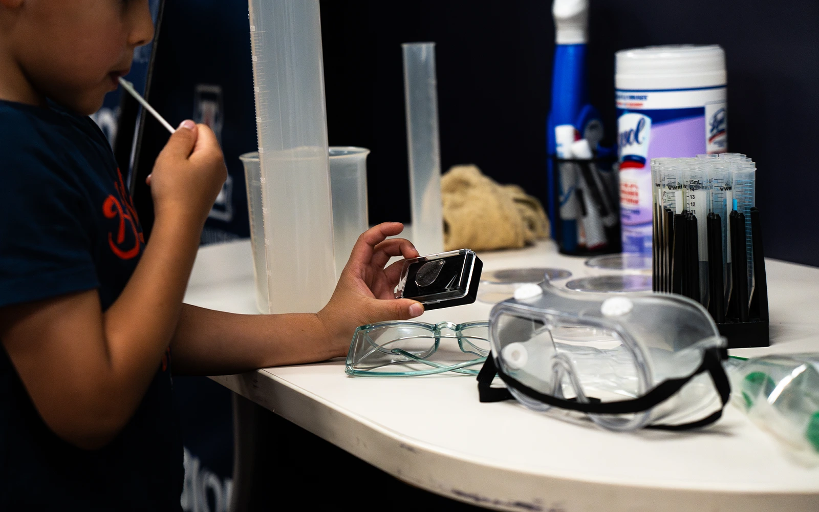 Child examining magnifying glass at photo booth prop table
