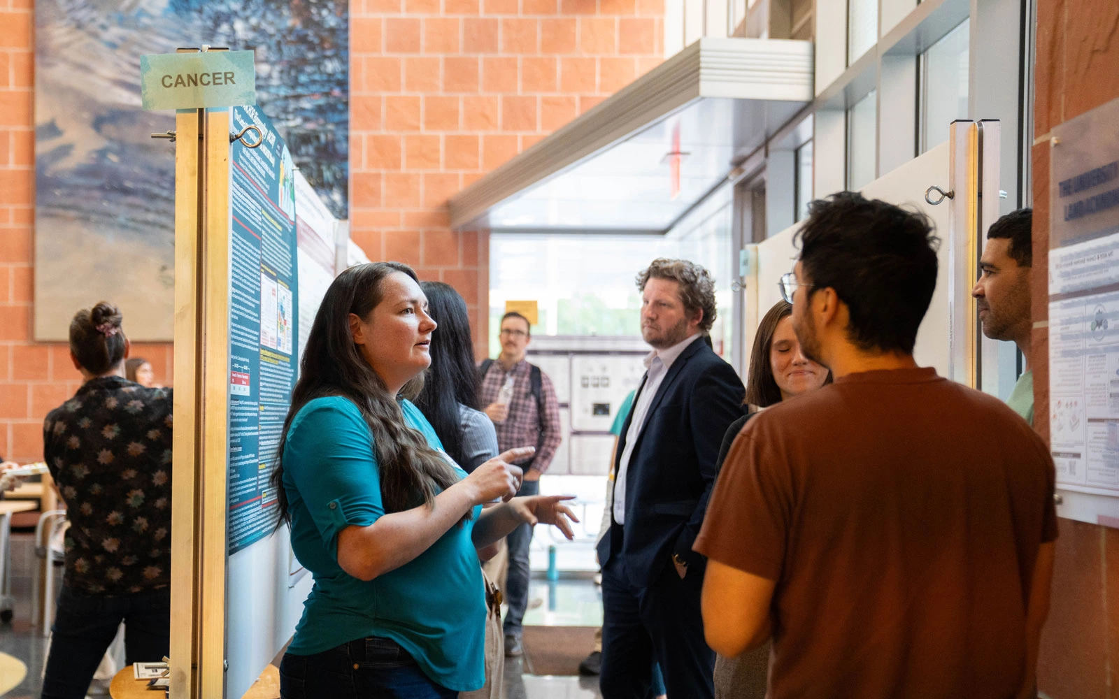 Individual presenting a research poster about cancer to a small group of attendees at a scientific conference.