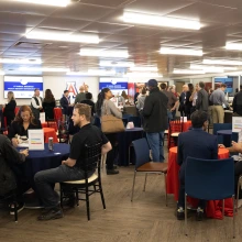 Faculty, industry partners, and community members are gathered in small groups connecting and engaging with each other. 