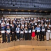 Group of individuals holding certificates in a tiered auditorium.