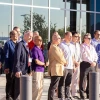 A group of professionals standing outside a modern building with large glass windows, under clear skies.