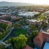 Aerial view of the University of Arizona campus showing red-roofed buildings, green lawns, and surrounding cityscape during sunset.