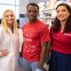 Three people in a laboratory, one wearing a white lab coat and the other two in red shirts, smiling at the camera.