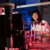 A woman smiling next to a lab with red lights.