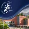 A modern building with large windows and a brick facade is surrounded by greenery under a clear sky. In the top left corner, there is a blue graphic with the text: "Connect • Collaborate • Create 25 Years.