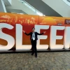 Person stands in front of orange and white sign spelling SLEEP